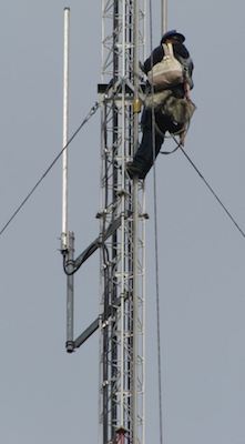 worker up high on the side of a telecom tower